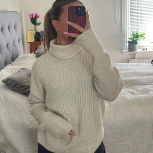 Beige ribbad polotröja - Säljer en mysig beige polotröja med ribbad struktur. Tröjan har lång ärm och en hög, vikt krage som ger en avslappnad och stilren look. Perfekt för kyligare dagar och enkel att matcha med olika outfits.
