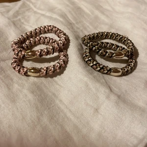 Två par spiralarmband i rosa och svart - Fyra spiralformade armband, två i ljusrosa och två i svart med guldiga detaljer. Perfekta som accessoar för att ge lite extra stil till din outfit.