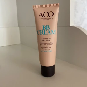 ACO BB Cream Soft Beige - BB Cream i nyansen Soft Beige från ACO. Ger en naturlig och matt finish, fungerar som en 5-i-1 produkt för att jämna ut hudtonen och återfukta. Passar alla hudtyper. Kommer i en beige tub med svart lock. 