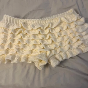 Vita virkade shorts med volanger - Supergulliga vita virkade shorts med flera lager volanger. Jag har gjort dom själv därav priset. Aldrig använda, endast testade.