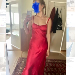 Röd satinklänning med smala axelband - Säljer en röd långklänning i satin med smala axelband och figurnära passform. Köpt på Zara 2024, men har inte kommit till användning så den är helt oanvänd! Klänningen har en enkel, elegant design med lätt glansigt material och öppen rygg. Perfekt för festliga tillfällen! 