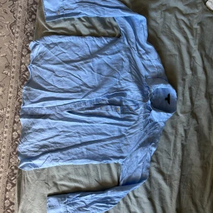 Massimo dutti linneskjorta  - Säljer en ljusblå skjorta i linne från Massimo dutti med klassisk krage och knäppning framtill. Skjortan har långa ärmar och en avslappnad passform, perfekt för varmare dagar.