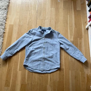 Ralph lauren skjorta  - En ljusblå Ralph lauren skjorta som är perfekt nu för dom varmare tiderna. Väldigt bra skick endast använd några gånger och inga fläckar. Nypris cirka 1000 beroende på vart man köper den ifrån. Storlek 14-16 vilket motsvarar storlek cirka XS. Hör av er vid minsta frågor! Guds frid