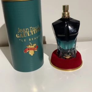 Jean Paul Gaultier Le Beau Le Parfum herrparfym - Säljer en Jean Paul Gaultier Le Beau Le Parfum i en snygg blågrön flaska formad som en manlig torso. Flaskan rymmer 75 ml och kommer med originalförpackning i grön och guld. Doften är intensiv och elegant. De finns ungefär 65 ml kvar 