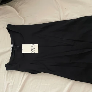 Svart klänning från Zara, storlek S - En stilren svart topp från Zara i storlek S. Toppen har en enkel och klassisk design med rund halsringning och kort ärm. Perfekt för dig som gillar minimalistisk stil och vill ha en mångsidig bas i garderoben.