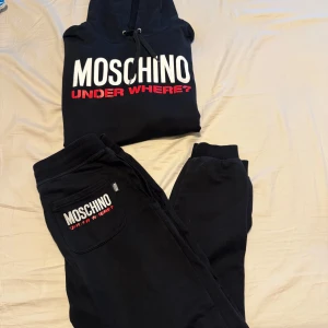 Svarta mjukisbyxor från Moschino - Svarta mjukisbyxor från Moschino Underwear med broderad logga på bakfickan i vitt och rött. Byxorna har resår och snörning i midjan samt muddar vid bensluten. Tillverkade i 100% bomull för en skön och avslappnad vibe.