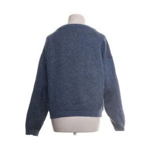 Blå stickad tröja från Acne Studios - Mysig blå stickad tröja från Acne Studios i oversized modell. Tillverkad i en lyxig mix av mohair och ull som ger en fluffig känsla. Tröjan har rund halsringning och långa ärmar, perfekt för lager-på-lager under kyliga dagar.