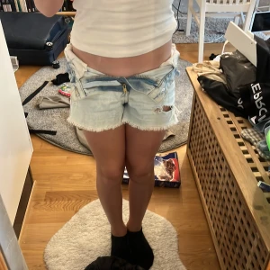 Ljusblå slitna jeansshorts  - Säljer ett par ljusblå jeansshorts med råa fransade kanter och slitningar (hål) framtill. Shortsen har klassisk dragkedja och knapp. Strl 134 men passar mig som har 152-158 så de e jättestora i storleken.