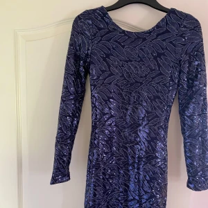 Midnattsblå paljettklänning Make Way XS - Säljer en midnattsblå kort klänning från Make Way med glittriga paljetter och mönster. Klänningen har lång ärm och en djup, öppen rygg som ger en riktigt snygg look. Perfekt för dig som vill sticka ut med stil! Klänningen är köpt för 399kr men säljs för 100kr. Prislappen är fortfarande på och klänningen är oanvänd. 