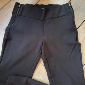 Zara Trafaluc collection L( upplever dem som S) - Eleganta svarta byxor från Zara Trafaluc collection. Byxorna har en hög midja och dragkedjor på sidorna. Storlek L men upplever dem S.  Mått upptill 35 cm. Från grenen 22 cm. Finns stretch i dem dock relativt hård