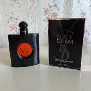 Yves Saint Laurent Black Opium 90ml - Black Opium från Yves Saint Laurent är en ikonisk parfym i en svart, glittrig flaska med rund orange detalj. Flaskan rymmer 90 ml och har en elegant, modern design. Doften är känd för sina djupa, sensuella toner och passar dig som gillar en stark signaturdoft.