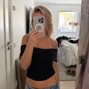 Svart offshoulder topp - Snygg svart offshoulder topp med croppad passform. Toppen är axelbandslös och sitter tight över överkroppen, enkel att matcha med jeans eller kjol & perfekt till sommarn. Toppen är från Gina Tricot