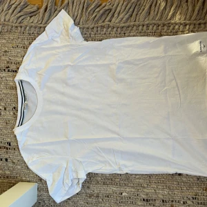 Vit basic t-shirt från Björn borh - Vit t-shirt från Björn borg klassisk modell med rund hals och diskret logga i nacken. Tillverkad i mjuk bomull och har korta ärmar. Perfekt för en clean och enkel stil.