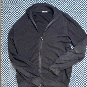 Brun kofta från OGER med dragkedja - Snygg mörkgrå kofta från OGER Italian Knitwear. Tröjan har hel dragkedja framtill, ribbade muddar och krage. Tillverkad i mjukt stickat material som passar perfekt till jeans eller chinos. Enkel och stilren design som funkar året runt. Nypris hela 298€ men köpt för 109€ på rea. Priset är ej hugget i sten