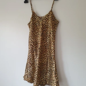 Leopardmönstrad nattklänning strl S - Snygg kort slipklänning med leopardmönster och tunna axelband. Klänningen har en figurnära passform och är tillverkad i ett glansigt, lätt material som ger en cool och trendig look. Perfekt för dig som vill sticka ut med ett djurmönster.  Helt & fint skick