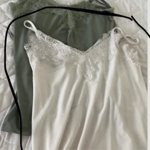 Vit spetslinne   - OBS: man kan även köpa båda 2 samtidigt. Supersöt vit linne med tunna axelband och vacker spets upptill. Linnet har en mjuk, silkeslen känsla och en feminin v-ringning. Perfekt för dig som gillar romantisk och stilren look.