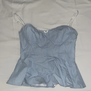 Zara topp - Snygg blå korsett-topp med tunna vita ränder och smala axelband med spets. Toppen har bystformade kupor och liten rosett framtill. Perfekt för dig som vill ha en feminin och trendig look.