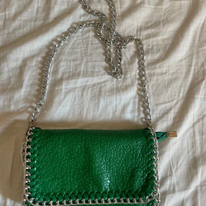 Tiago axelväska - Grön axelväska från Tiamo i skinnimitation med silverfärgad kedja som axelrem. 