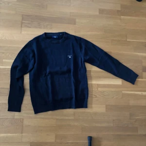 Mörkblå stickad tröja från Gant - Säljer en klassisk mörkblå stickad tröja från Gant med rund halsringning och diskret logga på bröstet. Storlek S