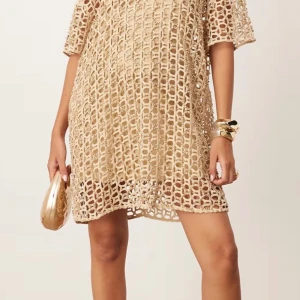 Beige kortklänning - Jättefin kort smyckad klänning från ASOS EDITION. Klänningen är ny med lappen kvar och den är köpt för 1200kr. Underklänningen medföljer! 