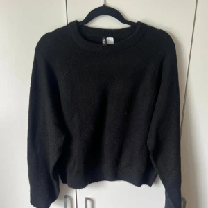 Svart stickad tröja - En enkel svart stickad tröja med rund halsringning och långa ärmar. Perfekt basplagg som passar till det mesta och är lätt att matcha med andra kläder. Tröjan har en mjuk och lite lös passform.