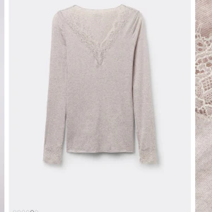 Intemissme tröja - Säljer en beige långärmad topp med v-ringning och fina spetsdetaljer vid halsringning och ärmslut. Toppen har en mjuk och stretchig känsla, perfekt för en stilren och feminin look. Typ aldrig använd