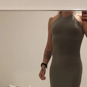 Grå tight ärmlös klänning - Säljer en grå tight klänning med hög hals och ärmlös design. Klänningen är figurnära och har en enkel, stilren look som passar perfekt för dig som gillar minimalistisk stil.