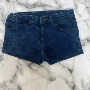 Mörkblå jeansshorts från Ellos - Snygga mörkblå jeansshorts från Ellos med klassisk femficksdesign och knappgylf. Shortsen har en normal passform och är tillverkade i denim. Perfekta för sommaren och enkla att matcha med olika toppar.