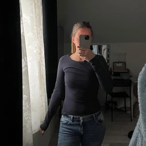 Blå långärmad topp - Säljer en blå långärmad topp i stretchigt material. Enkel och stilren design med rund halsringning, perfekt att matcha med jeans eller kjol. Passformen är tight och materialet känns mjukt mot huden. Sytt in själv vid midjan eftersom jag ville ha den tightare, ordentliga sömmar