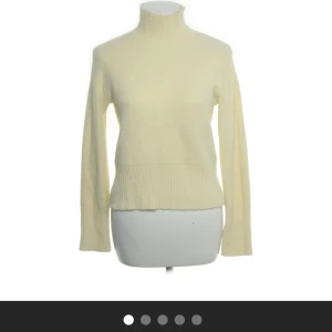 Ljusgul stickad polotröja - Säljer en ljusgul stickad polotröja med lång ärm och ribbade detaljer vid hals, ärmslut och nederkant. Perfekt för kyligare dagar och enkel att matcha med olika outfits. Köpt på sellpy med prislapp kvar.