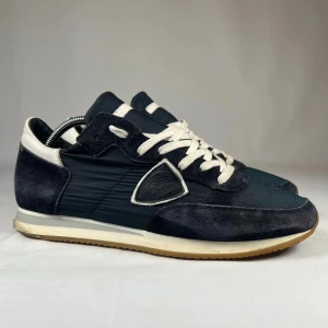 Philip model - Snygga mörkblå sneakers med vita snören och detaljer. Ovandel i mocka och syntet, med rund tå och platt sula. Perfekta för en stilren vardagslook.