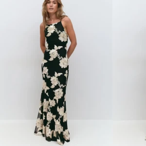 Svart långklänning med blommigt mönster - Svart långklänning med vita blommor från Gina, prislappen kvar och endast testad. Stretchig i materialet <3 Uprsprungspris 699 kr