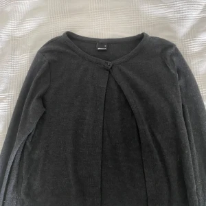 Mörkgrå kofta från Gina Tricot - En enkel och stilren mörkgrå kofta från Gina Tricot. Koftan har lång ärm, rund halsringning och knäpps med en knapp framtill. Använd 1 gång💞 är storlek M men tycker att den sitter som en S