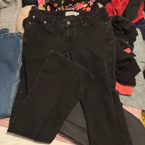 Svarta jeansbyxor från Junkyard - Svarta jeansbyxor från Junkyard med klassisk femficksdesign och raka ben. Byxorna har normal passform och är tillverkade i ett mjukt denimtyg. Perfekta för en avslappnad och stilren look.