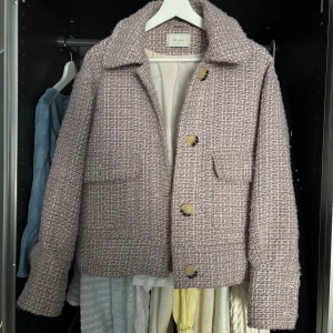 Rosa tweedjacka från Neo Noir - Säljer en as snygg rosa tweedjacka från Neo Noir med stora knappar framtill och två fickor. Jackan har klassisk krage och är fodrad med ljus insida. Storlek S men passar även M 