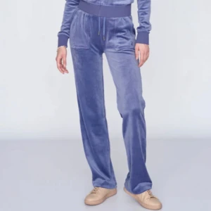 Blå mjukisbyxor i velour - Säljer ett par blå mjukisbyxor i mjuk velour med resår och dragsko i midjan. Byxorna har raka ben och fickor framtill. Perfekta för en avslappnad stil.