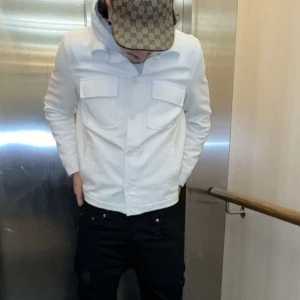 Vit overshirt med fickor - Snygg vit overshirt med klassisk krage och snygga bröstfickor. Perfekt att bära öppen över en t-shirt eller stängd som skjorta. Enkel och stilren design som passar till många outfits.