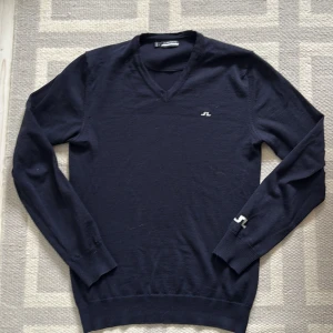 V-ringad J.Lindeberg tröja  - Säljer en stilren mörkblå v-ringad tröja från J.Lindeberg. Nu pris 1400 mitt pris 400