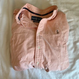 Ralph Lauren Classic Fit skjorta – laxrosa M -  Snygg och klassisk skjorta från Ralph Lauren i laxrosa. Passform: Classic Fit. Passar M. Använd få gånger – i bra skick. Nypris ca 1100 kr.  ✅ 100% bomull ✅ Fräsch färg som sticker ut ✅ Perfekt till sommar, fest eller stilren vardag  📦 Skickas spårbart så snabbt som möjligt!  💬 Fråga gärna om du undrar något!