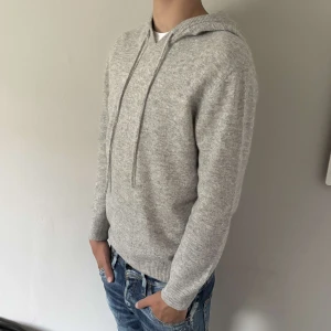 Ljusgrå merinoull hoodie - Säljer en ljusgrå stickad hoodie från GardeGrisch. Tröjan har huva med snörning och är långärmad. Perfekt för dig som gillar en clean och laidback stil. Materialet är mjukt och skönt, passar till allt!