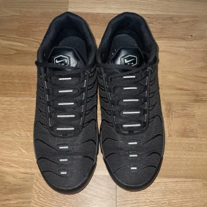 Nike Tn - Nike Air Max Plus Tn sneakers i helsvart med mesh och syntetpaneler, ikoniska vågformade detaljer och synlig Air Max-dämpning i sulan. Tn Air-logga på hälen och diskreta Swoosh-loggor på sidorna. Grymt streetwear vibe och riktigt bekväma.