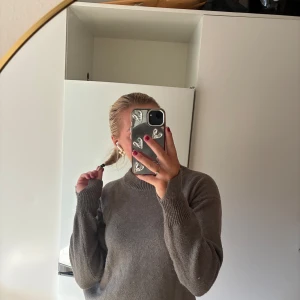 Brun stickad tröja med rund hals - Mysig brun stickad tröja med rund halsringning och långa ärmar. Tröjan har en relaxed passform och ribbade muddar vid ärmslut och nederkant. Perfekt för lager-på-lager och chill dagar.