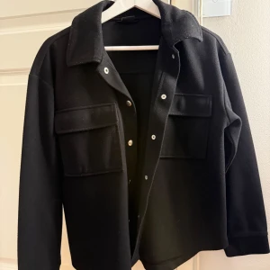 Svart overshirt med fickor och knappar - En tunn kappa som är från Gina. Använder den inte då jag köpte en ny. 