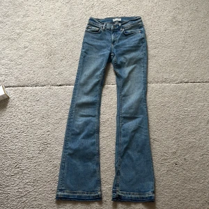 Blå bootcut jeans från gina trikot😍 - Snygga ljus- blå bootcut jeans från gina trickot i klassisk denim. Jeansen har fem fickor, normal midja och utsvängda ben. Sömmen där nere ör uppsprättade och där med är byxorna lite längre. Innerbenslängden är 81 cm och midjemåttet från sida till sida är 34 cm ungefär🌟