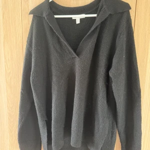 Svart stickad tröja med krage H&M XS - Svart stickad tröja från H&M i storlek XS. Tröjan har en snygg krage och v-ringning, samt långa ärmar. Perfekt för lager-på-lager och chill vibes. Enkel att matcha med jeans eller kjol.