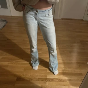 Ljusblå bootcut jeans från Lee - Säljer ett par ljusblå jeans från Lee med bootcut passform. Jeansen har klassisk femficksdesign, dragkedja och knapp med Lee-logga. Tillverkade i jeansmaterial och har en snygg, lite utsvängd siluett. Perfekta för dig som gillar retrovibbar och ljusa denimtoner.