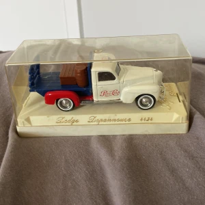 Dodge Depanneuse Pepsi Cola - Cool samlarmodell av en Dodge Depanneuse med Pepsi Cola-logga, perfekt för dig som gillar retrobilar och nostalgi. Modellen är detaljerad och levereras i originalförpackning – en unik inredningsdetalj eller present till bilentusiasten!