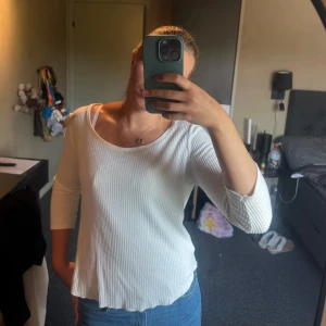 Vit ribbad långärmad tröja - Säljer en vit ribbad långärmad tröja med rund halsringning och trekvartsärm. Tröjan har en avslappnad passform och är perfekt att styla med jeans eller kjol. Enkel och stilren design som funkar till många olika looks.