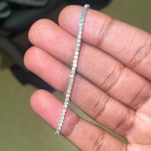 Glittrigt silverfärgat tennisarmband - Superfint och smalt tennisarmband i silverfärg med gnistrande stenar längs hela bandet. 