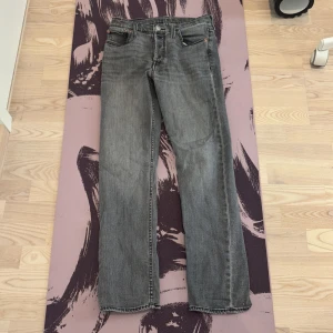 Levi's 501 grå jeans straight fit - Grå Levi's 501 jeans med klassisk straight fit och fem fickor. Jeansen har en snygg tvättad look, normal passform och ikonisk läderpatch bak i midjan. Perfekta för dig som gillar en tidlös stil med edge.